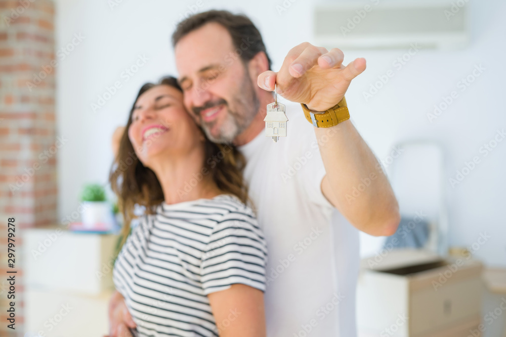 Middle age senior romantic couple holding and showing house keys, hugging and smiling happy for moving to a new home Middle age senior romantic couple holding and showing house keys, hugging and smiling happy for moving to a new home