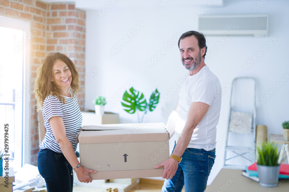 Middle age senior couple moving to a new house, holding cardboard boxing smiling happy in love with apartmant Middle age senior couple moving to a new house, holding cardboard boxing smiling happy in love with apartmant