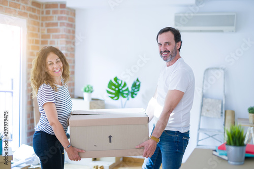 Middle age senior couple moving to a new house, holding cardboard boxing smiling happy in love with apartmant © Krakenimages.com