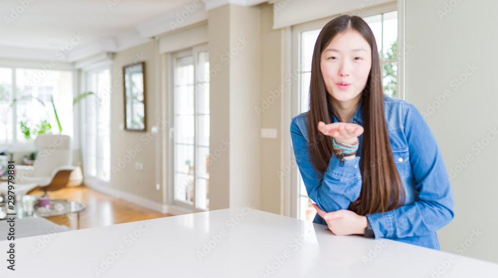 Young beautiful asian woman with long hair wearing denim jacket looking at the camera blowing a kiss with hand on air being lovely and sexy. Love expression. Young beautiful asian woman with long hair wearing denim jacket looking at the camera blowing a kiss with hand on air being lovely and sexy. Love expression.