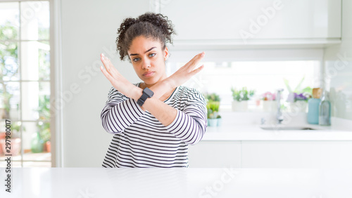 Beautiful african american woman with afro hair wearing casual striped sweater Rejection expression crossing arms doing negative sign  angry face