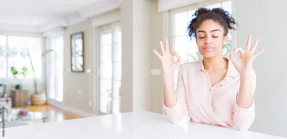 Wide angle of beautiful african american woman with afro hair relaxed and smiling with eyes closed doing meditation gesture with fingers. Yoga concept. Wide angle of beautiful african american woman with afro hair relaxed and smiling with eyes closed doing meditation gesture with fingers. Yoga concept.