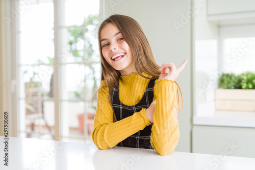 Free Download Young beautiful blonde kid girl wearing casual yellow sweater at home with a big smile on face, pointing with hand finger to the side looking at the camera. - GFXLoad