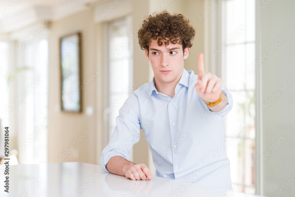 Young business man with curly read head Pointing with finger up and angry expression, showing no gesture