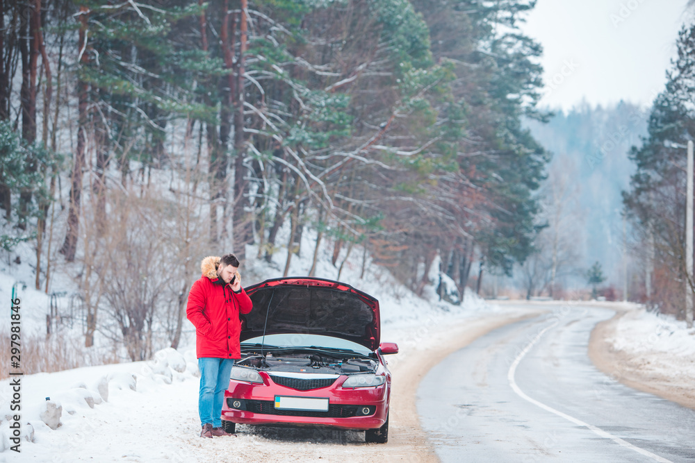 man standing near broken car with opened hood calling help