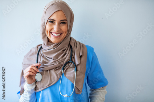 Confident female nurse. Confident Muslim female doctor standing with isolated gray. Closeup portrait of friendly, smiling confident muslim female doctor. Portrait of Muslim nurse with stethoscope photo