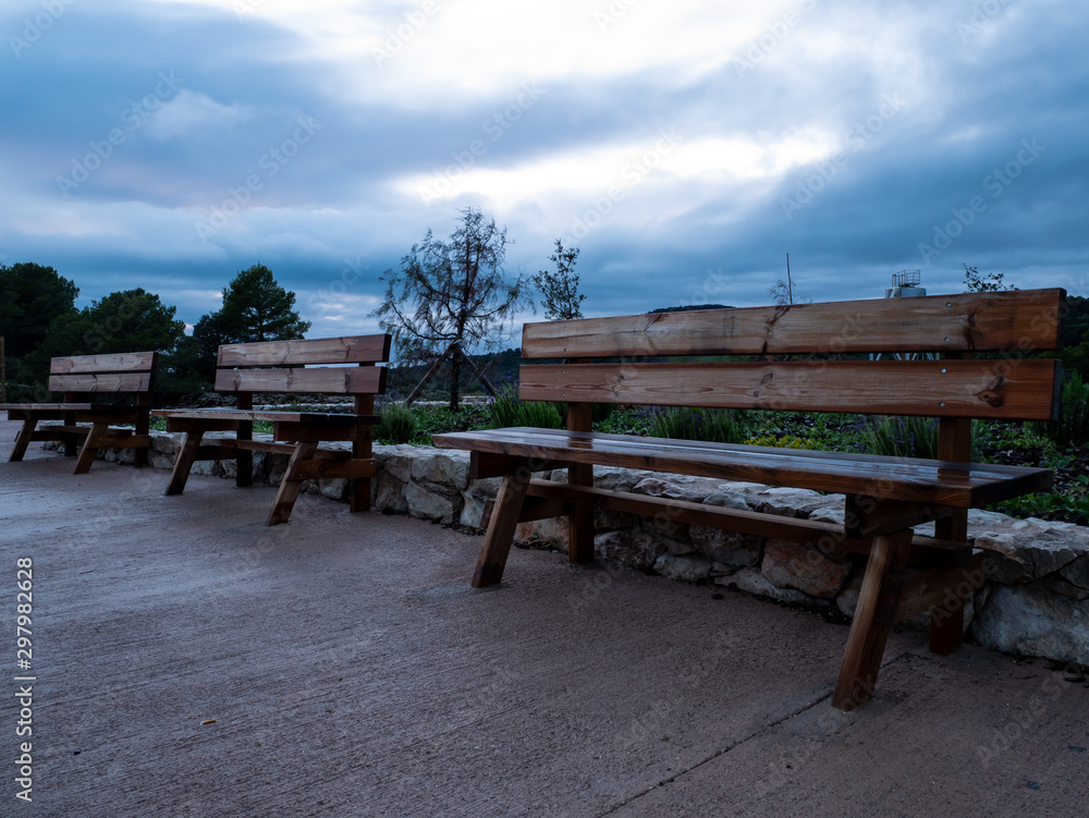  three wooden benches lined up in rainy sunset