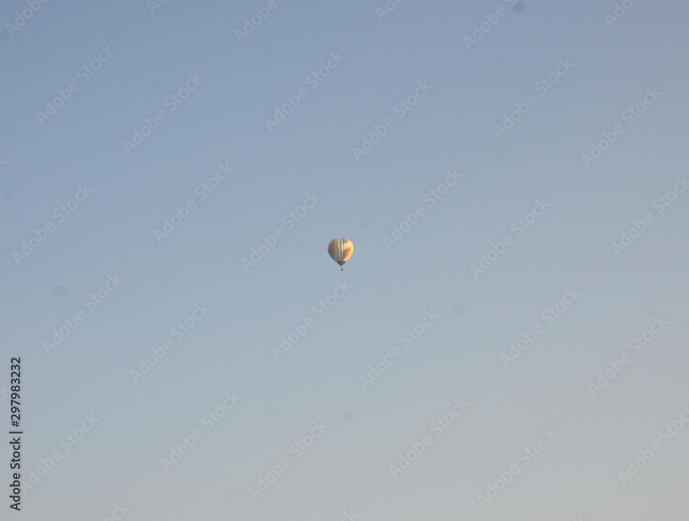 High in the blue sky is a multi-colored balloon. High in the blue sky is a multi-colored balloon.