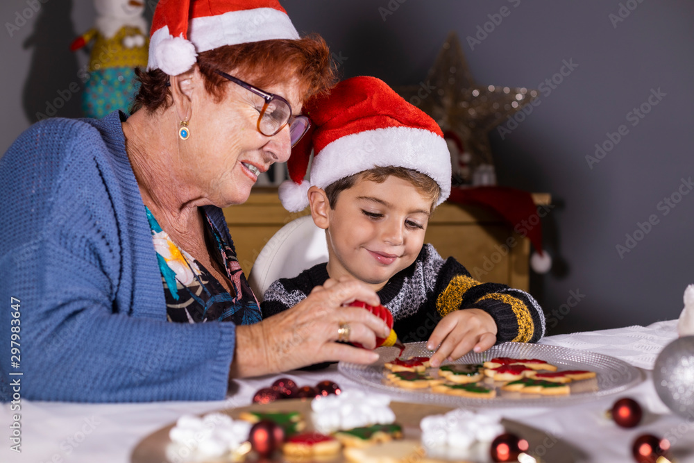 Grandmother and grandson decorating cookies on Christmas time Grandmother and grandson decorating cookies on Christmas time