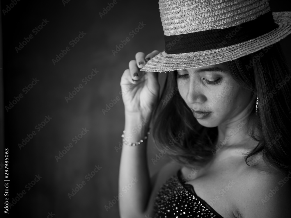 Portrait of Asian woman wearing dress and hat, black and white filter.