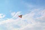 A rainbow kite flying against a blue sky and clouds using for the way to success and milestone concept.
