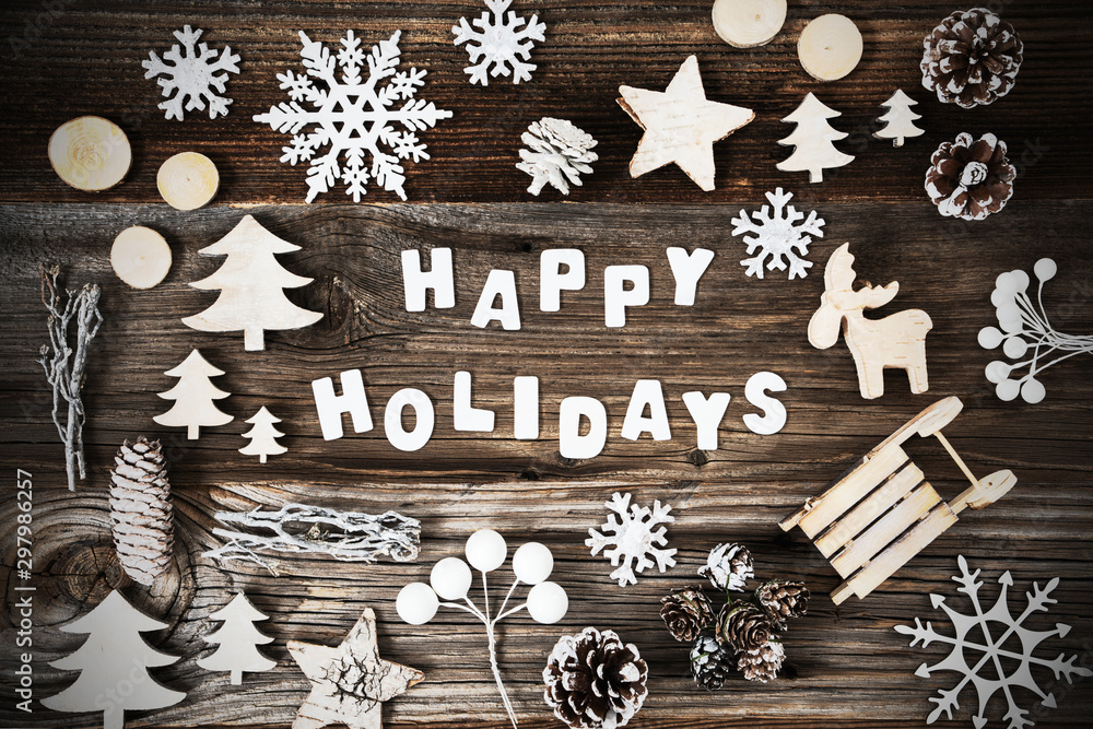 Fototapeta premium White Letters Building The Word Happy Holidays. Brown Wooden Background. Wooden Christmas Decoration Like Tree, Sled And Star