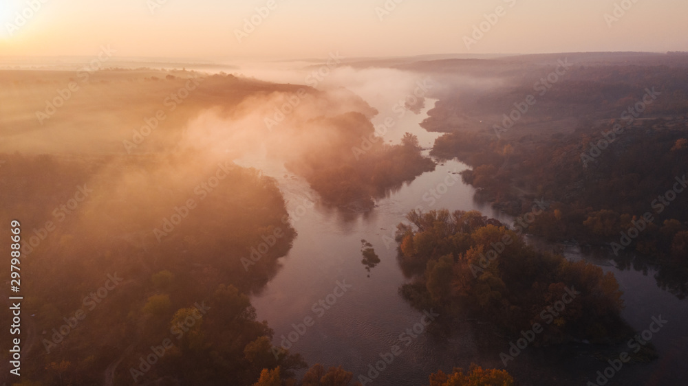 Fototapeta premium amazing aerial view on sunrise. foggy river and golden trees. beautiful autumn landscape. drone shot, bird's eye