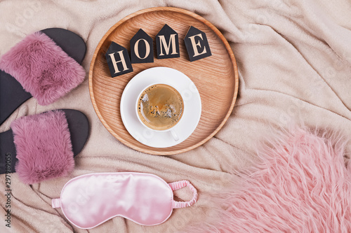 Creative composition with coffee, slippers, slipping mask and wooden letters arranged into a word Home