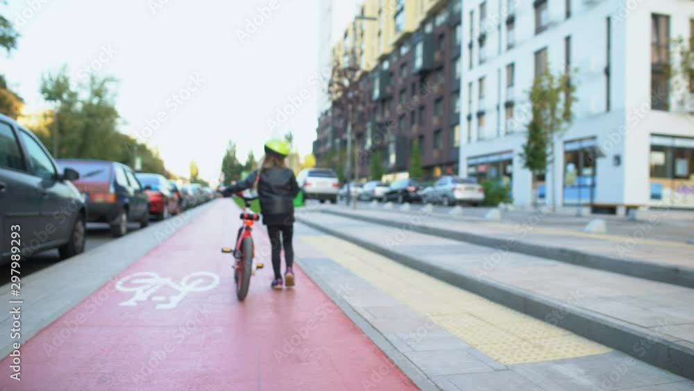 Little tired girl rolling bicycle on bike city track, active lifestyle and hobby Little tired girl rolling bicycle on bike city track, active lifestyle and hobby