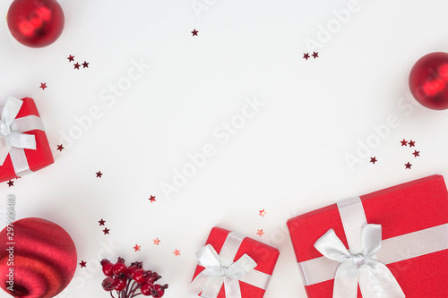 Frame from red Christmas gifts, balls, star confetti, berries branch on white background. Congratulation, Happy New Year concept. Top view, flat lay, copy space