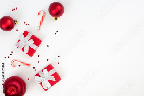 Red Christmas gifts, balls, star confetti, candy canes on white background. Congratulation, Happy New Year concept. Top view, flat lay, copy space