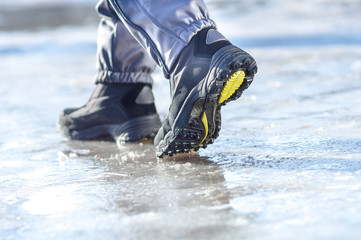 male or female winter boots walking on snowy sleet road