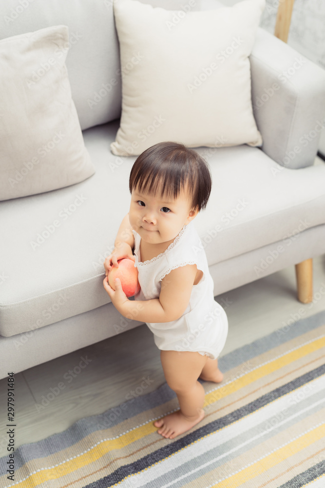 Cute little baby girl standing next to sofa at living room Cute little baby girl standing next to sofa at living room