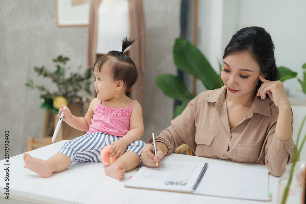 Little assistant. Little baby girl using pen while sitting on office desk with her mother in office Little assistant. Little baby girl using pen while sitting on office desk with her mother in office