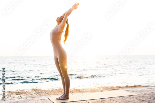 Beautiful woman outdoors on beach make stretching exercise.