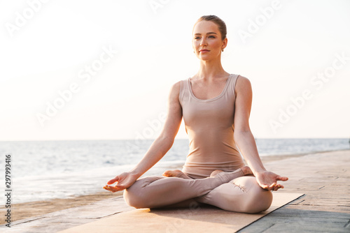 Fotografie Fitness woman meditate outdoors on beach.