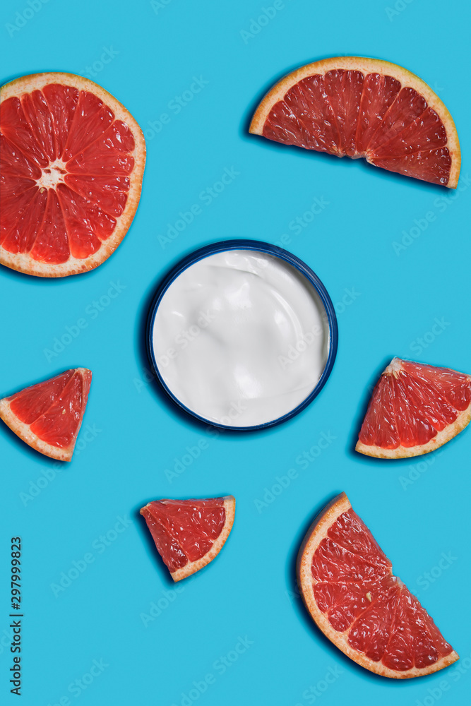 white cream in a jar with grapefruit on blue background. beauty and health care concept. Minimalistic flat lay with copy space. Top view. Cosmetic natural skin care white cream in a jar with grapefruit on blue background. beauty and health care concept. Minimalistic flat lay with copy space. Top view. Cosmetic natural skin care