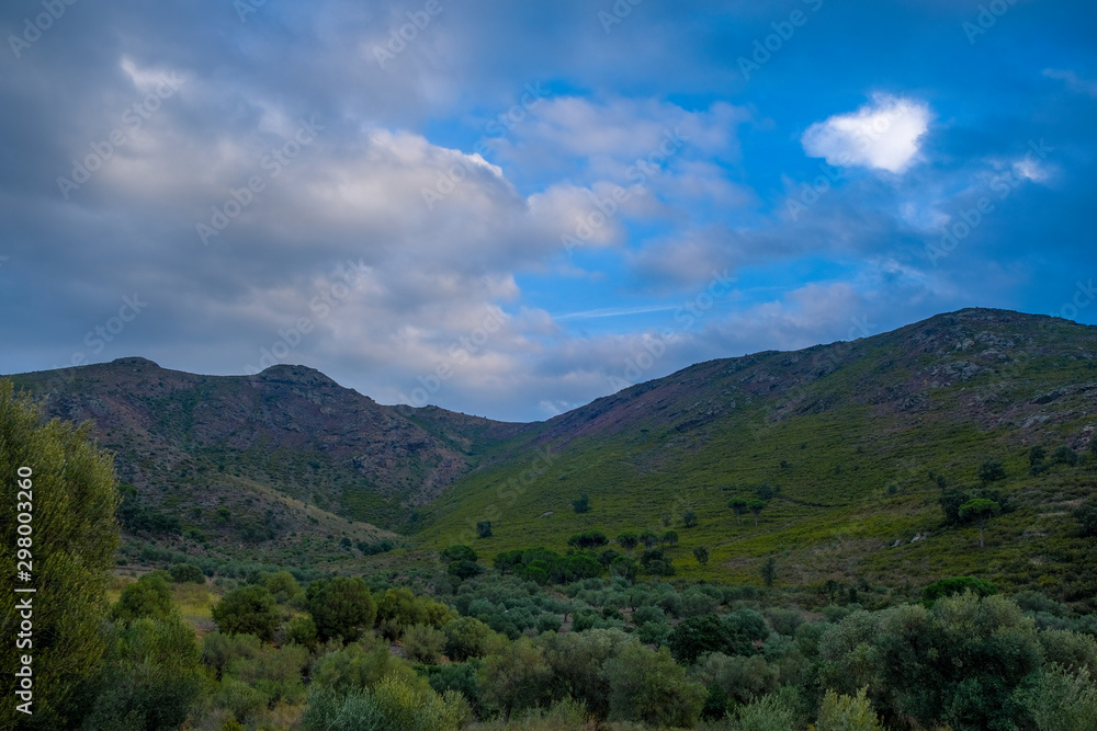 Mountain landscape on blue cloudy sky background. Mountain meadows in the setting sun. Night descends in the Pyrenees. Mediterranean landscape.