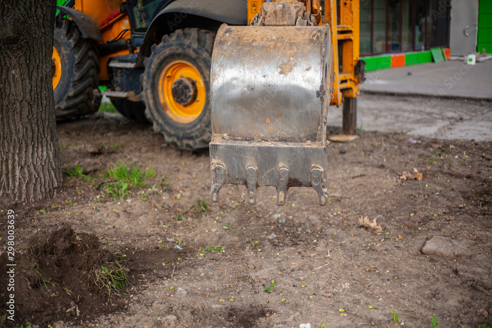 The bucket of the tractor digs the ground. Heavy equipment at work. Metal bucket close-up. The bucket of the tractor digs the ground. Heavy equipment at work. Metal bucket close-up.