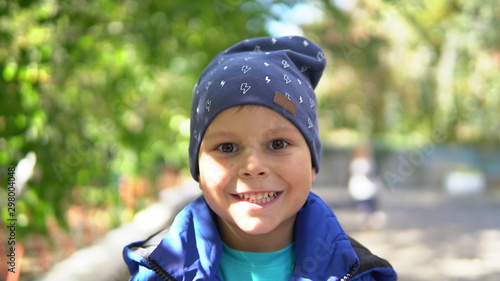 Little smiling child in blue hat in the kindergarden in autumn
