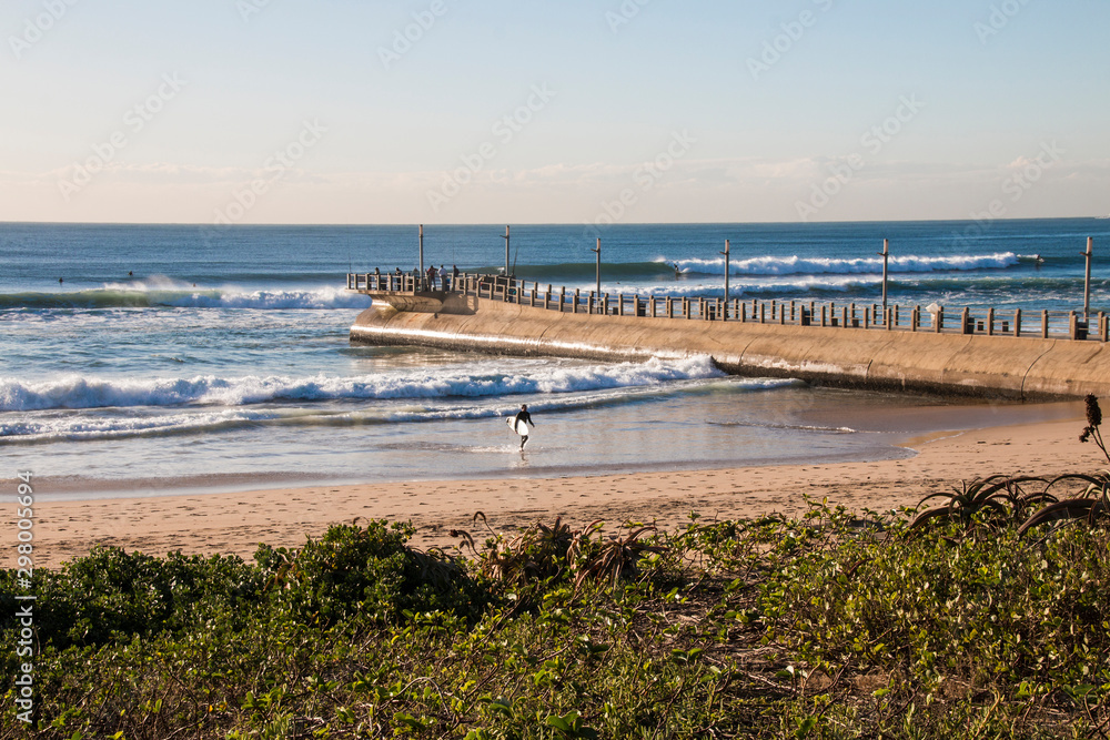 Pier Stretching into Sea with Fishermen and Surfer