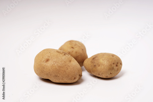 Three fresh brown potatoes raw isolated white background