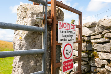 Detailed view of Warning signs at the entrance to a right of way in the Yorkshire Dales. Dog walkers must keep dogs on leads to prevent scaring the cows.