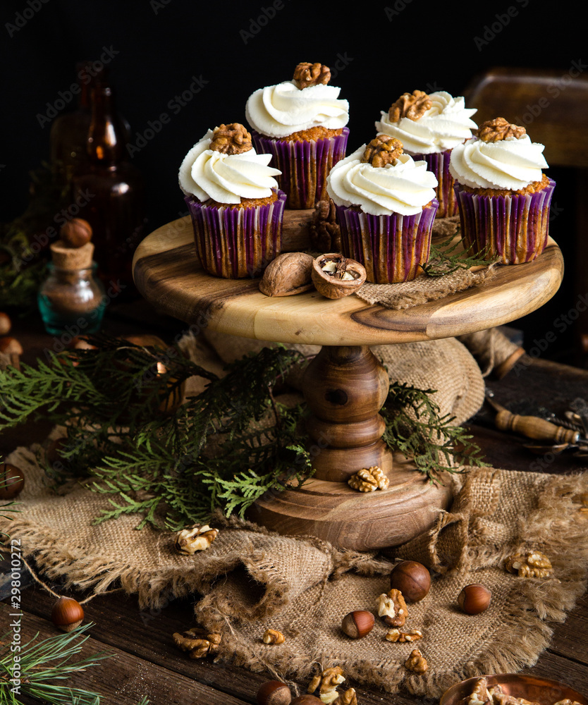 Fototapeta premium homemade carrot or pumpkin cupcakes with white cream and walnut on top 