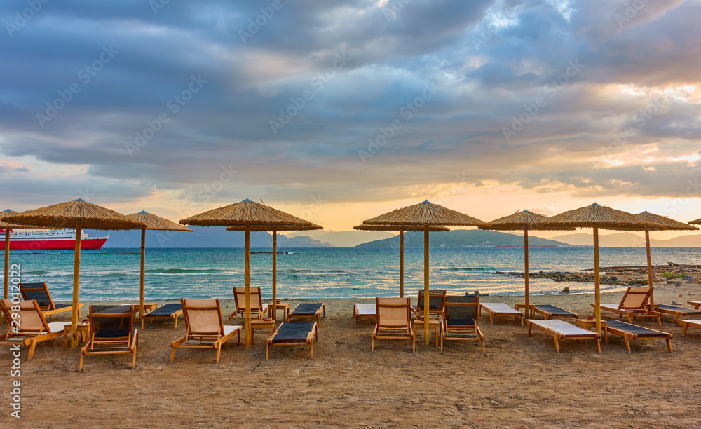 Panorana of empty beach with deck chairs and umbrellas at sunset