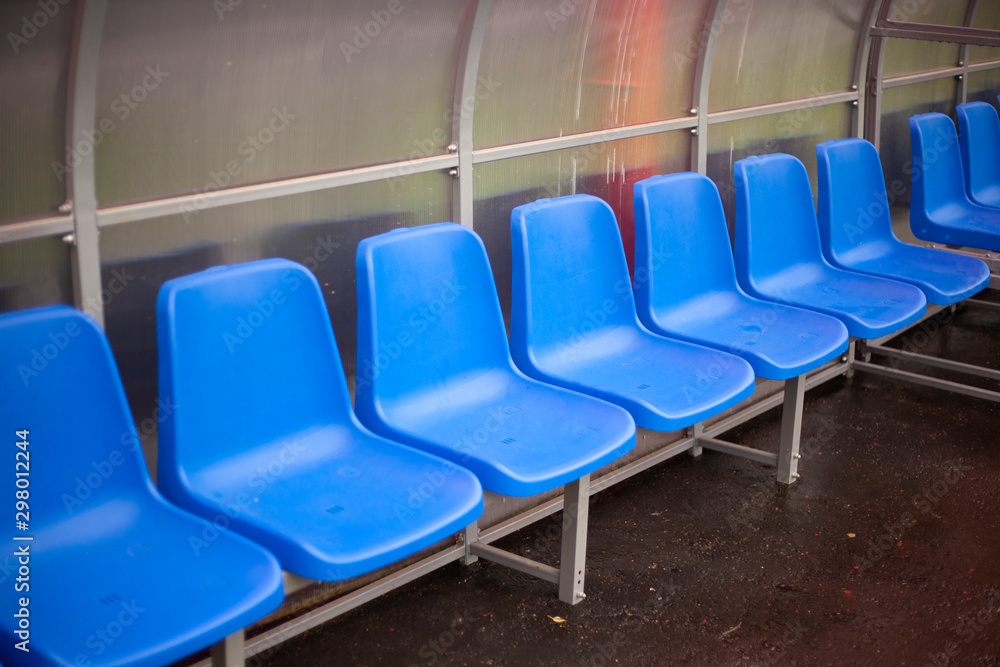 Fototapeta premium A row of blue chairs in a stadium. A place for a trainer. Armchairs where the team sits.