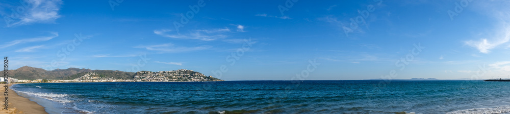 Seascape in Roses, Catalunya, Spain. City on the coast on blue sky and mountain background. Beautiful sandy beach panoramic view in the sunny day, natural background. The bay and the city 