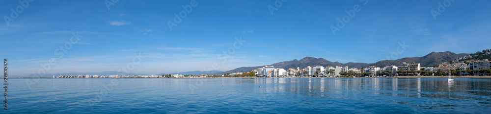 Seascape in Roses, Catalunya, Spain. City on the coast on blue sky background. Beautiful panoramic view in the sunny day, natural background. The bay and the city.