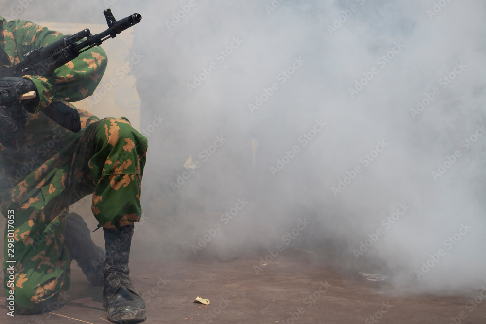 Naklejka premium The soldier is preparing to attack. The smoke of war and the military awaits directions. Machine gun barrel at war. Demonstration performance of the military.