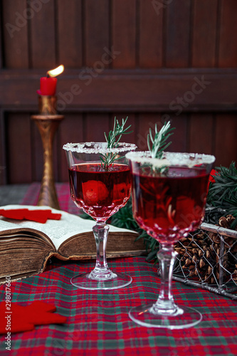 Christmas still life   two glass with red raspberry beverage decorated with rosemary   vintage old fashion style.