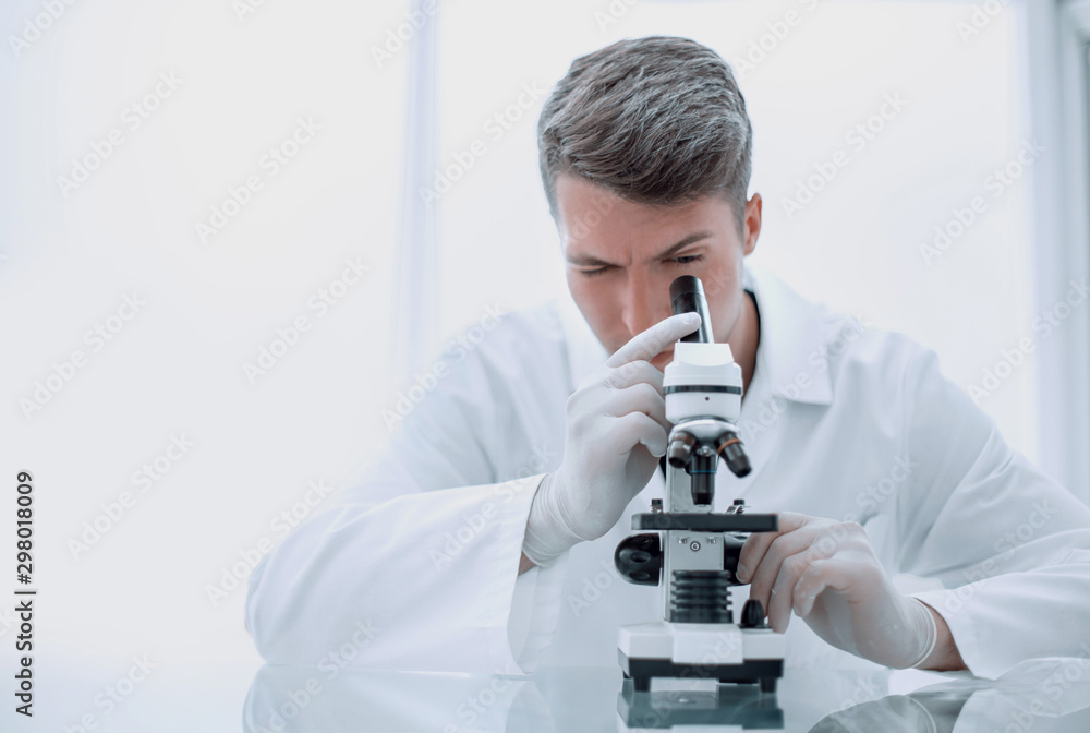young scientist with a microscope sitting at a laboratory table young scientist with a microscope sitting at a laboratory table