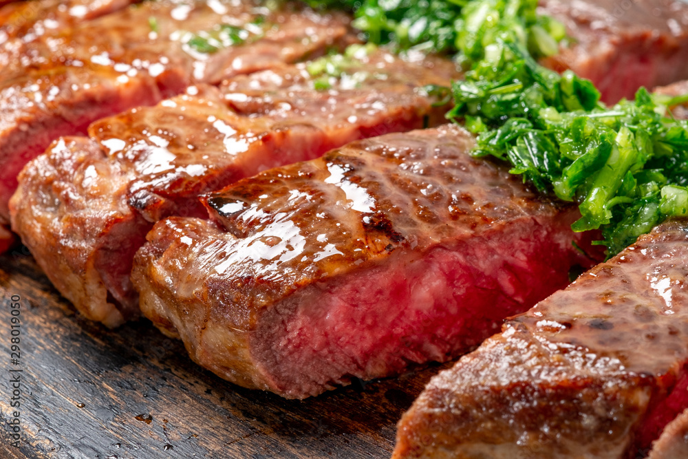 Roast sliced beef Steak medium rare Striploin with chimichurri sauce close up Roast sliced beef Steak medium rare Striploin with chimichurri sauce close up