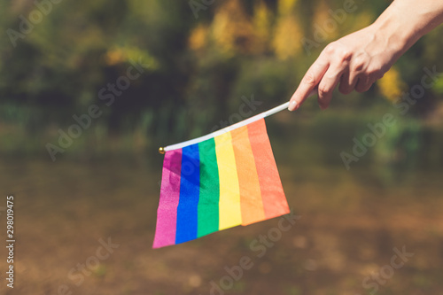 Female holding rainbow pride gay flag outdoors.
