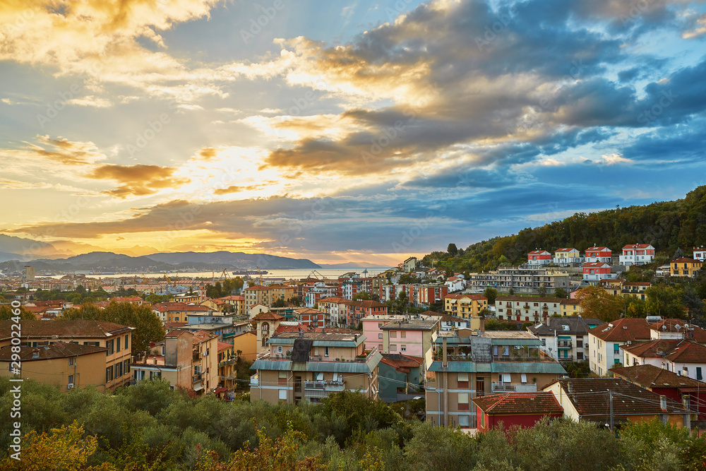 Dramatic sky with clouds and sun beams during sunrise in La Spezia