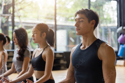 Close up group of adult people practicing yoga in the class.