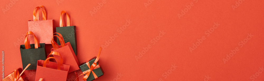 Top view of gift boxes and shopping bags on red background with copy space, panoramic shot - obrazy, fototapety, plakaty 