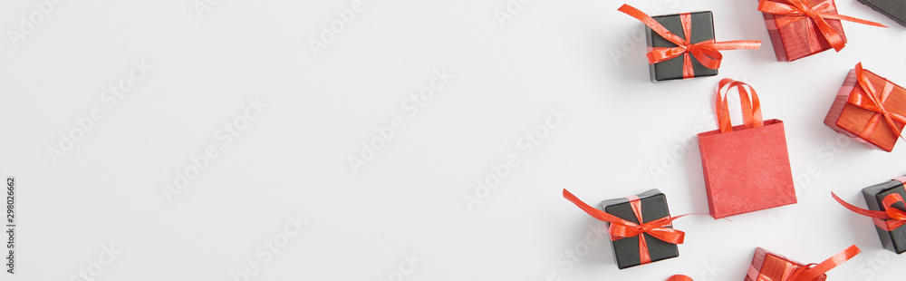 top view of black and red presents and shopping bag on white background, panoramic shot - obrazy, fototapety, plakaty 