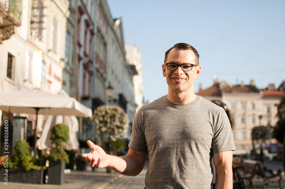 Half body shot of young man in a street of an old town in Europe looking in the camera with brown eyes and eyesglasses Half body shot of young man in a street of an old town in Europe looking in the camera with brown eyes and eyesglasses