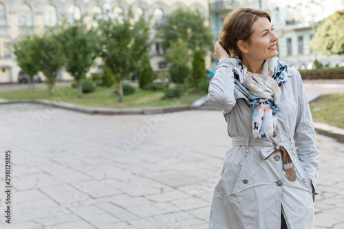 Portrait of a happy smiling adult woman over city background. Place for text.