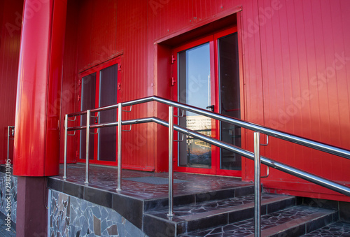 Red office building of a business center with door and steps.